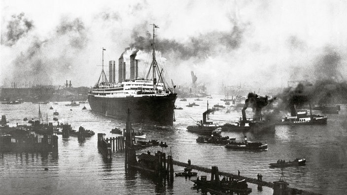 Schwarzweiß-Bild: Ein riesiges Dampfschiff bei der Ausfahrt aus dem Hamburger Hafen | Bildquelle: picture-alliance/Imagno Schwarzweiß-Bild: Ein riesiges Dampfschiff bei der Ausfahrt aus dem Hamburger Hafen