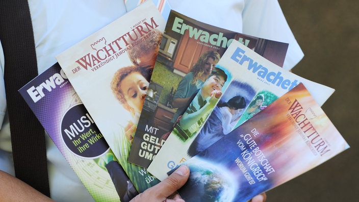Die Zeitschriften "Erwachet" und "Wachturm" werden aufgefächert von einer Person gehalten. | Bildquelle: dpa/Arne Dedert Die Zeitschriften "Erwachet" und "Wachturm" werden aufgefächert von einer Person gehalten.